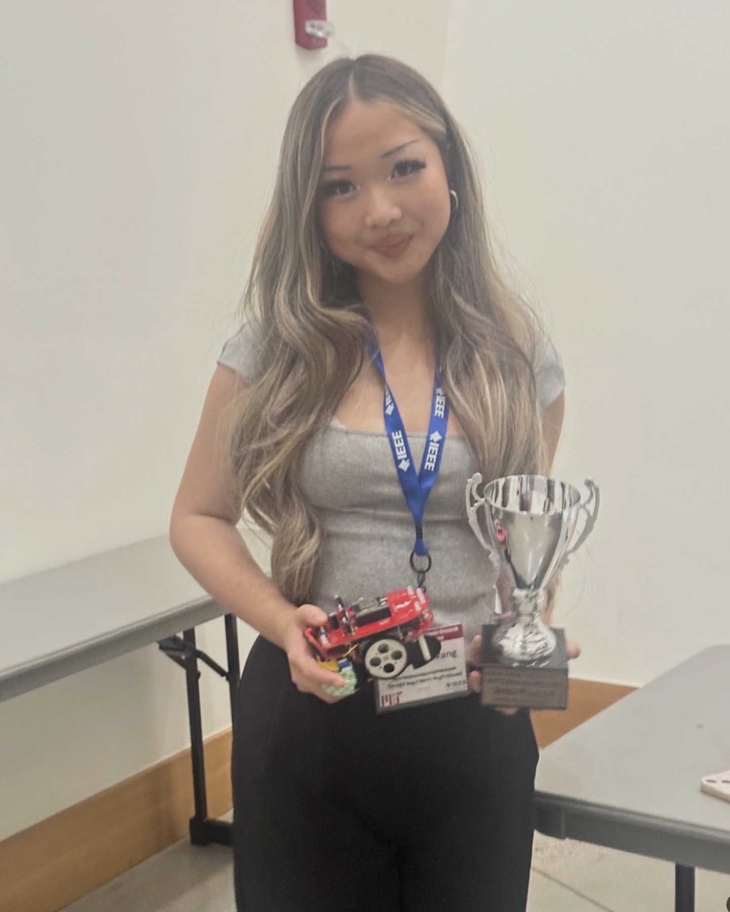 Veronika Wang holding her micromouse robot and the trophy at the IEEE MIT Micromouse competition
