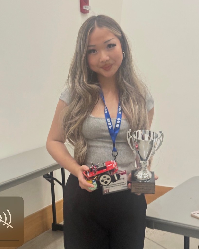 Veronika Wang holding her micromouse robot and competition trophy